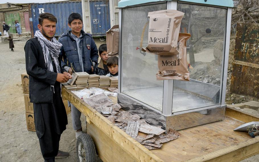 Children at a cart outside Bagram Airfield, Afghanistan sell items from Meals, Ready to Eat, the food rations issued to U.S. troops, in March 2021. Much of the economy nearby is dependent on what the base discards.  


