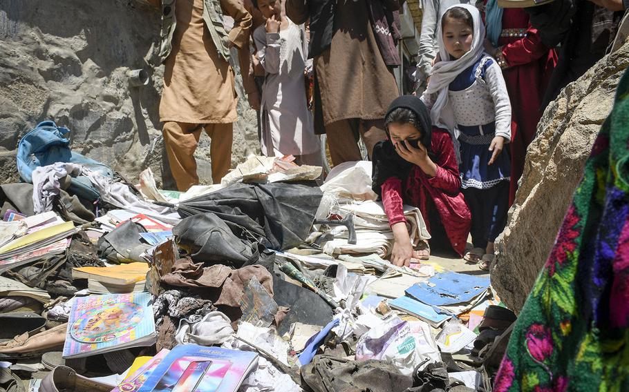 School children pick through items left behind after a deadly attack on the Syed Al-Shahda school in west Kabul, Afghanistan, including notebooks riddled with holes and discarded clothing. The Saturday attack left at least 50 dead and more than 100 wounded, a statement by the Afghan Interior Ministry said on Sunday, May 9, 2021.