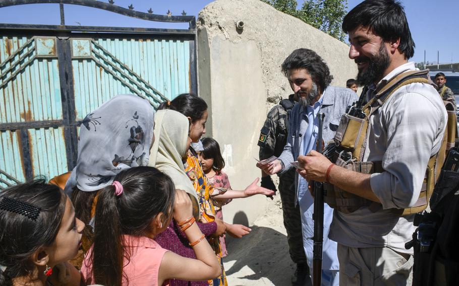Hussain Qadri, an adviser to the governor of the province of Logar in Afghanistan, gives 100 Afghani bills, worth about $1.29, to children in a Taliban-contested village during a cease-fire May 14, 2021. Qadri grew up in the village but has not been able to visit his childhood home in two years due to heavy fighting. 