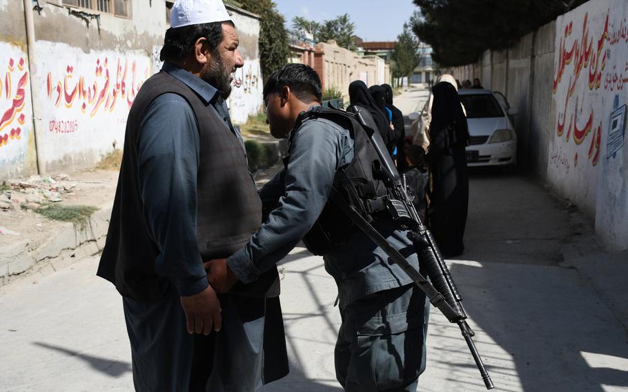 A police officer searches a man near the entrance of a polling center in Kabul on Saturday, Sept. 28, 2019. 