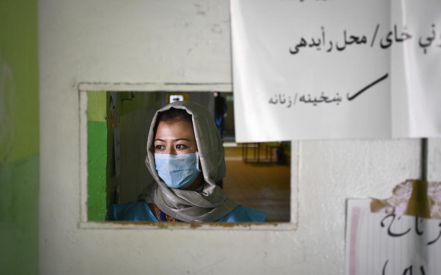 Shakila, 20, an election worker at a polling station in downtown Kabul, waits for women to vote in Afghanistans presidential election on Saturday, Sept. 28, 2019. She sits near signs that say "Voting area / women."