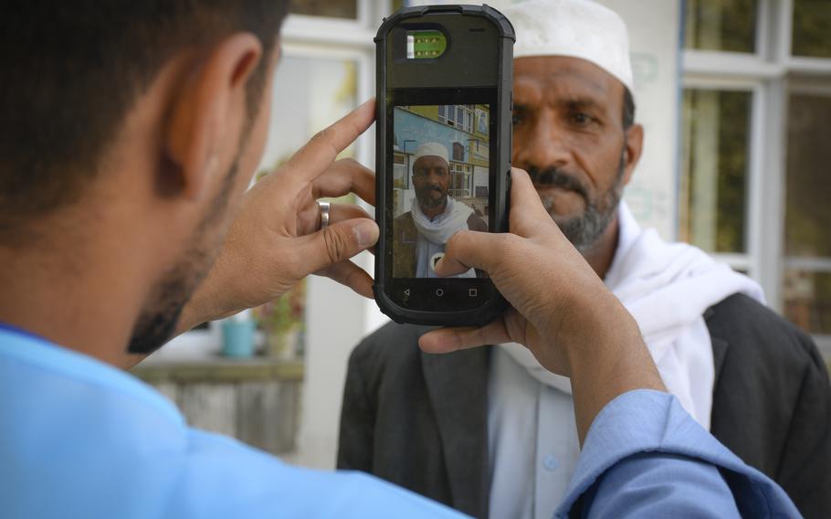 An election worker checks prospective voter Mohammed Bashir, 54, using a biometric scanner during Afghanistan's presidential election on Saturday, Sept. 28, 2019.