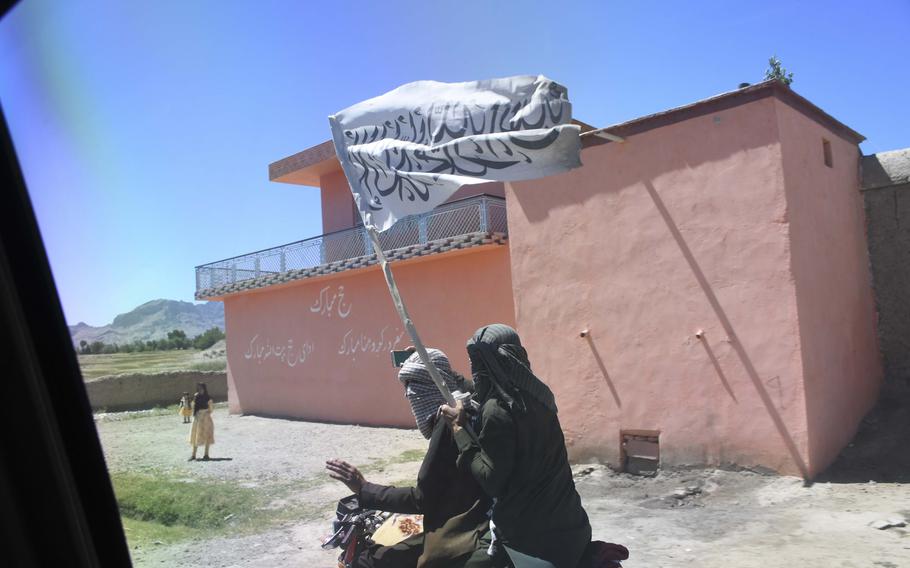 A man flying a Taliban flag passes soldiers of the Afghan National Army’s 203rd Corps as they venture to a Taliban stronghold in Logar province, a mission only made possible by unprecedented mutual cease-fires between the Taliban and the Afghan government over the weekend.