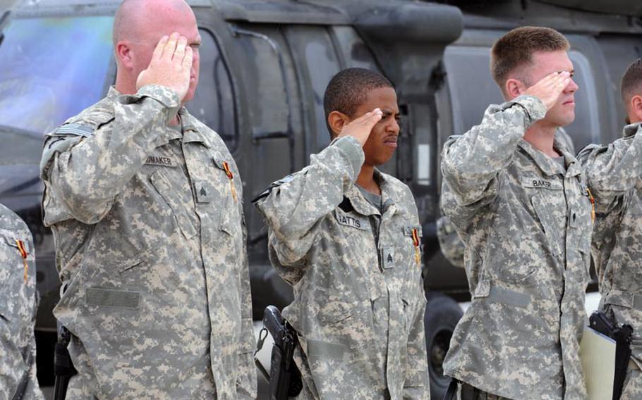 Left to right, U.S. Army Sgt. Steven Schumaker, Sgt. Antonio Gattis and Spc. Matthew Baker with the 5th Battalion, 158th Aviation Regiment salute during the national anthem on May 12 after receiving Germany&#39;s Gold Cross in Kunduz, Afghanistan.