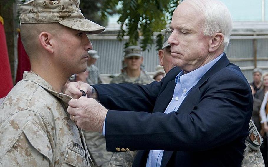 Sen. John McCain promotes Marine Staff Sgt. Antonio Aburto during a ceremony at Camp Eggers in Kabul on Sunday. McCain and Sens. Lindsey Graham and Joe Lieberman helped present several combat infantry badges to troops.