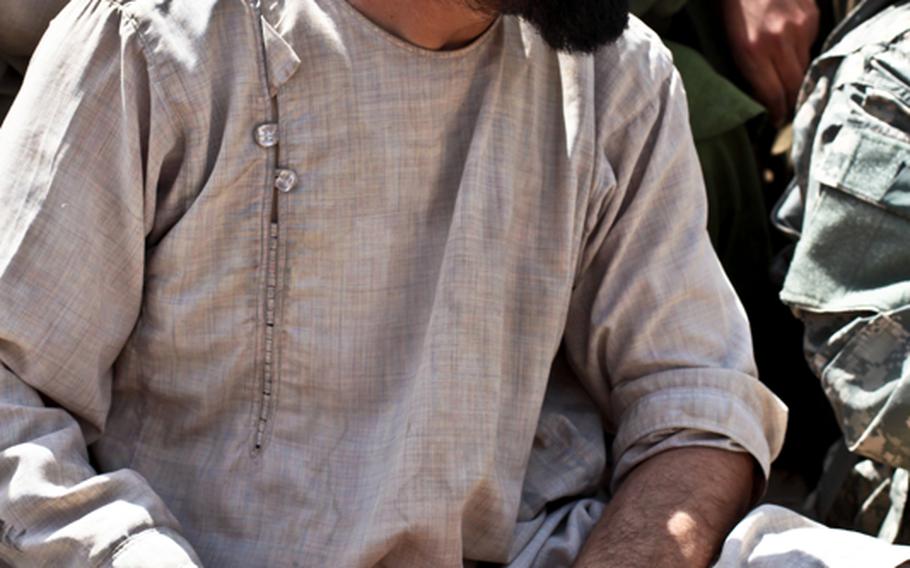 Ghosadeen, who commands a "village security team" of about two dozen men, holds a pistol as he talks to U.S. and Canadian troops outside the village of Zormashor, in Dand district, Kandahar province. With U.S. troops and Afghan forces unable to reach many rural areas, they are turning to villagers to arm and protect themselves against the Taliban.