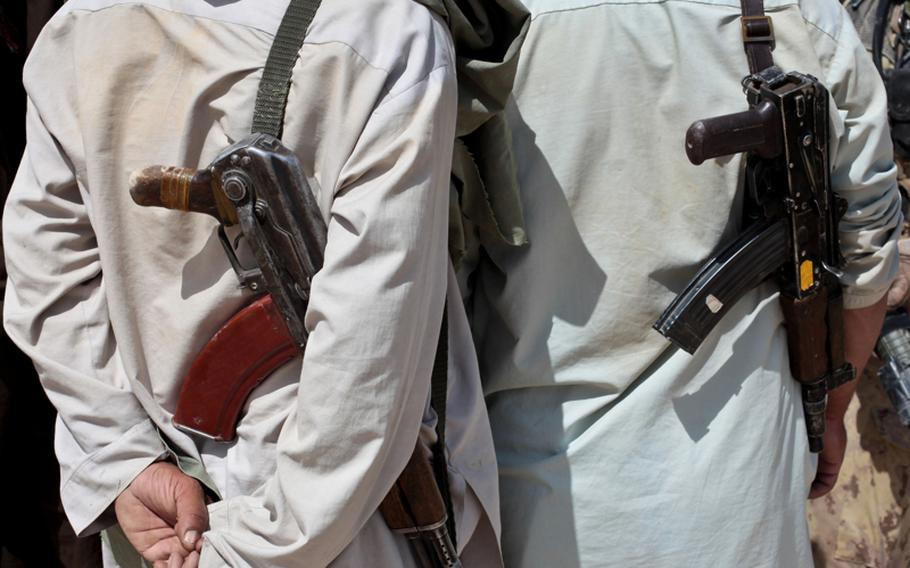 Villagers carry Kalashnikov rifles as they talk with U.S. and Canadian troops outside the village of Zormashor, in Dand district, Kandahar province, Afghanistan. With the U.S. and Afghan forces unable to reach many rural areas, they are turning increasingly to Afghan villagers to arm and protect themselves against the Taliban. June 27, 2010.