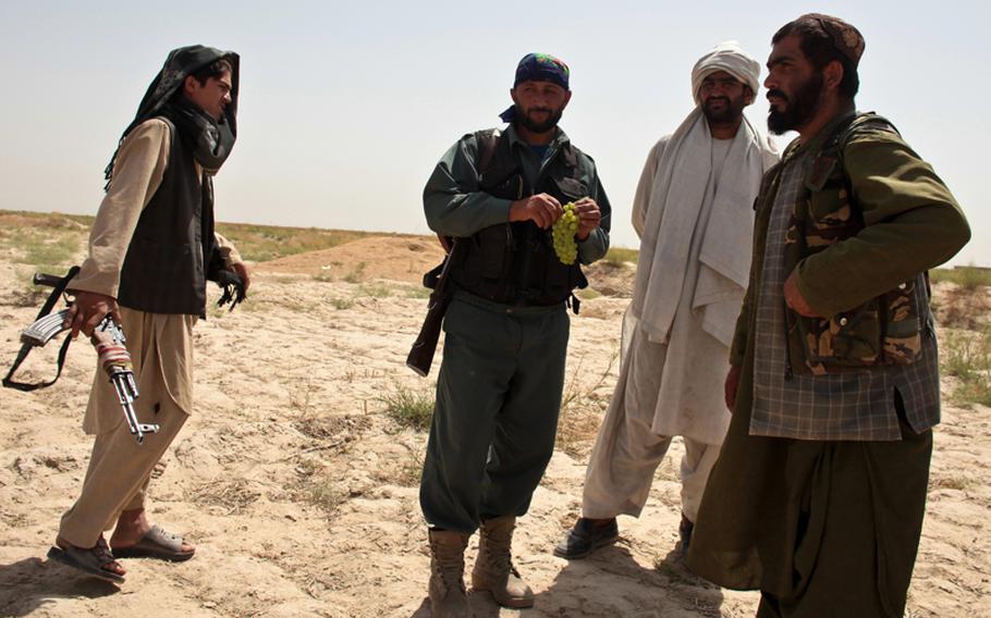 An Afghan policeman on patrol with U.S. and Canadian troops chats with three armed villagers outside Zormashor, in Dand district, Kandahar province, Afghanistan. With U.S. troops and Afghan forces unable to reach many rural areas, they are turning increasingly to village groups to arm and protect themselves against the Taliban. June 27, 2010.