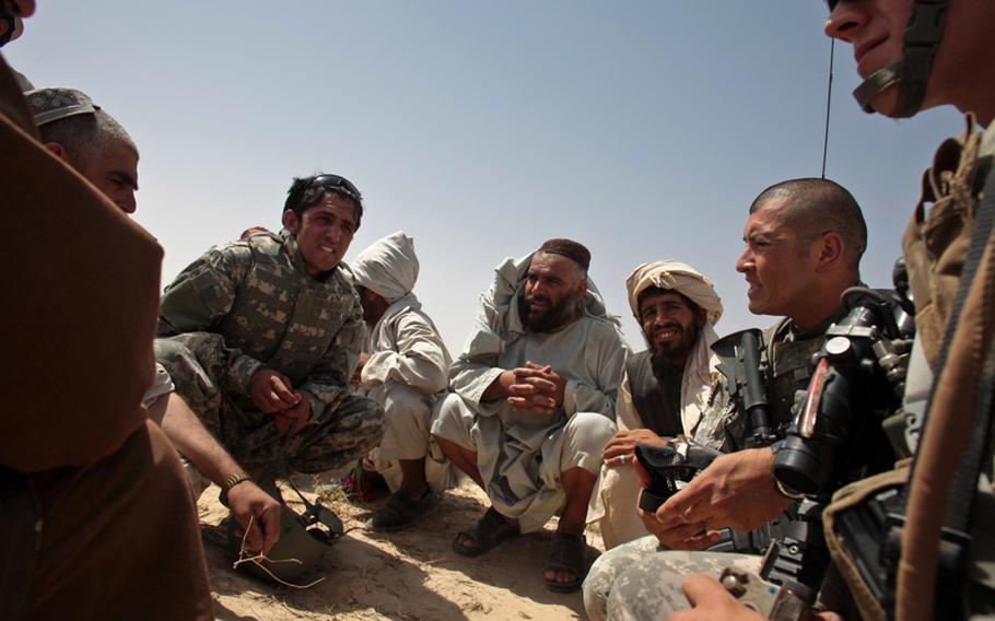 Staff Sgt. Julio Jurado, right, and other soldiers talk with armed men outside the village of Zormashor, in Dand district, Kandahar province, Afghanistan. With U.S. and Afghan government forces unable to reach many rural areas, they are turning increasingly to village groups to arm and protect themselves. June 27, 2010.