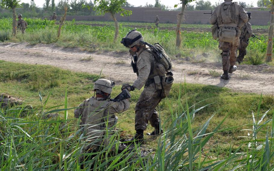 A Marine helps a comrade up the steep side of a canal ditch during an operation in search of an IED cache in Marjah District on June 25.