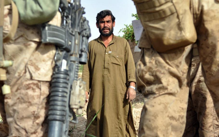 Marines question a farmer during an operation in search of a homemade bomb cache in Marjah District on June 25.