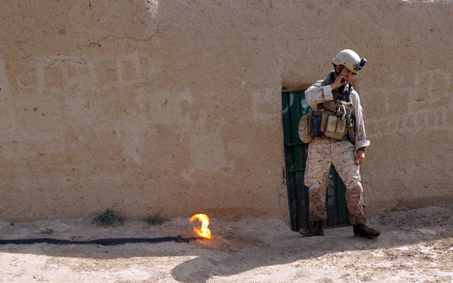 A Marine explosives technician drags off the cigarette he just lit with the fire he set to burn off gunpowder found buried inside a suspicious compound in Marjah District on June 25.