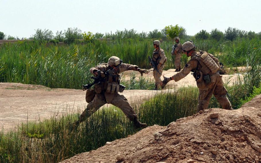 A Marine offers a hand to a comrade leaping an irrigation ditch during an operation in search of an IED cache in Marjah District on June 25.