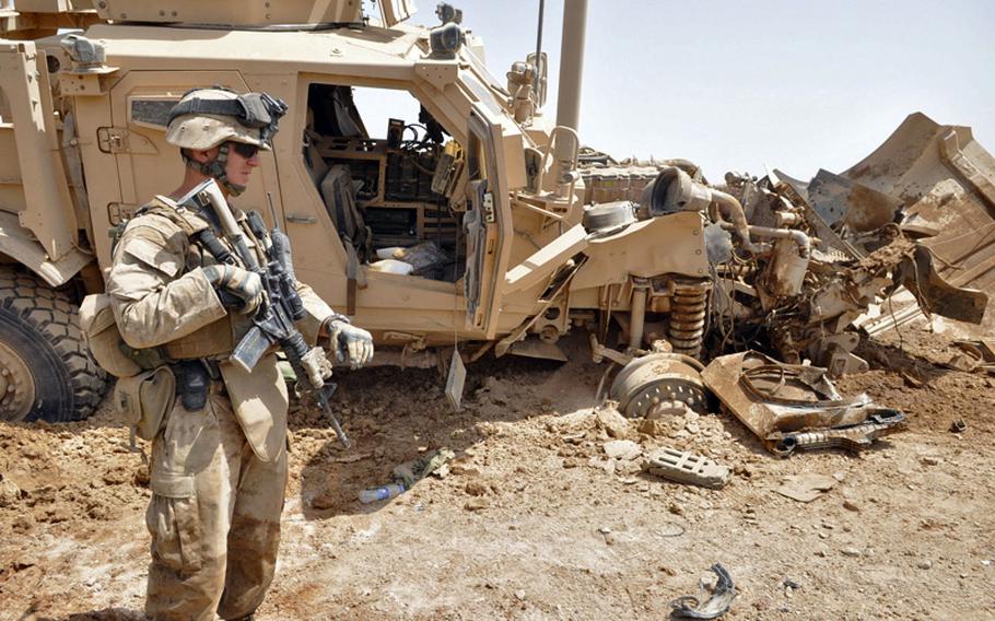 Platoon Commander 1st Lt. Dave Emison, 25, stands outside his armored vehicle after it hit a homemade bomb buried in the road on June 25, causing damage but only minor injuries.