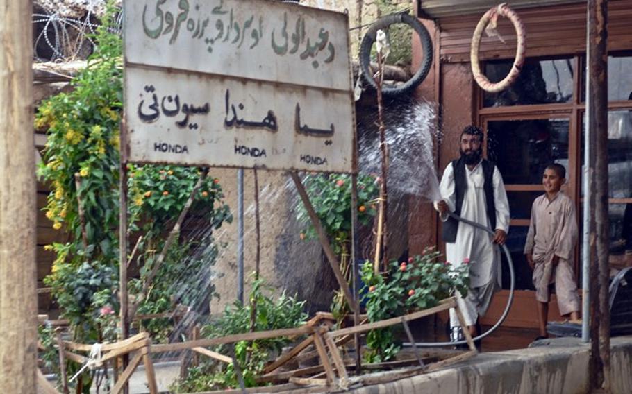 Shop owner Haji Abdul Walli waters the plants at his newly refurbished shop at the Koru Chareh Bazaar in Marjah District. The Marines paid local workers to fix up the shop after it was damaged in the February offensive.