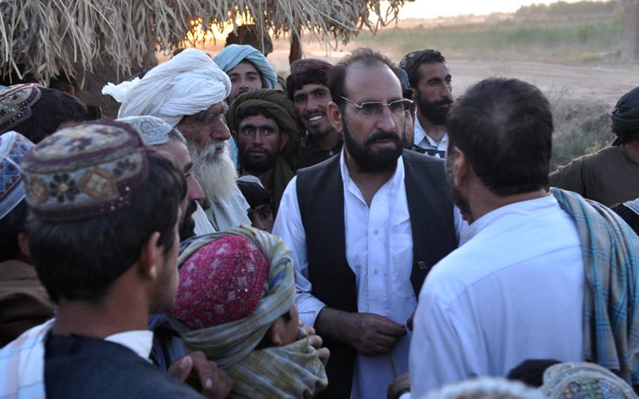 Marjah District Governor Haji Zahir talks to people at dusk on June 18, urging them to organize neighborhood watch programs to fight off the Taliban.