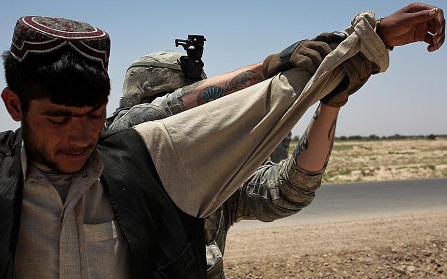 A soldier with 1st Squadron, 71st Cavalry Regiment searches a man at a traffic checkpoint in Dand district, Kandahar province, Afghanistan. June 18, 2010.