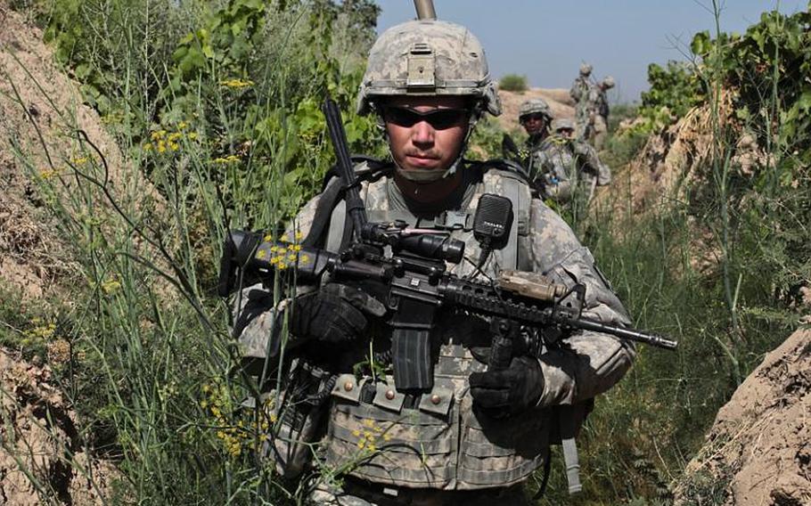 Sgt. Mitchel Stallings, of Troop B, 1st Squadron, 71st Cavalry Regiment, and other troops move through an irrigation trench in a grape orchard in Dand district, Kandahar province, Afghanistan. June 19, 2010.