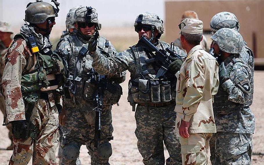 Members of the 1st Battalion, 327th Infantry Regiment Military Transition Team speak with Iraqi soldiers during a mission to find weapons caches in the desert near Bayji, Iraq, in this 2008 photo. The U.S. troops were responsible for training and advising two Iraqi battalions in the area.