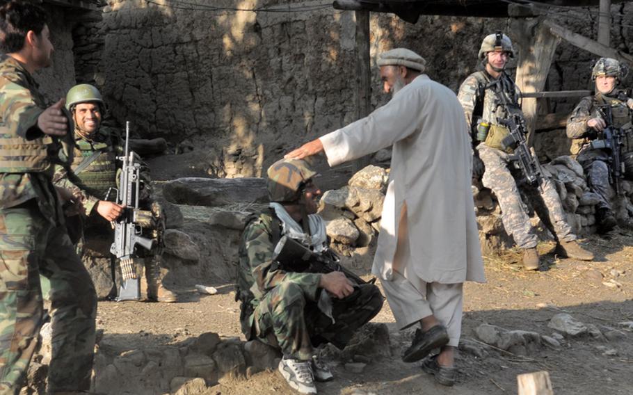 An elderly man in Kandagal village jokes with Afghan National Army soldiers on July 21 as U.S. troops look on. The village is just across the Pech River from the U.S. base, Combat Outpost Michigan.