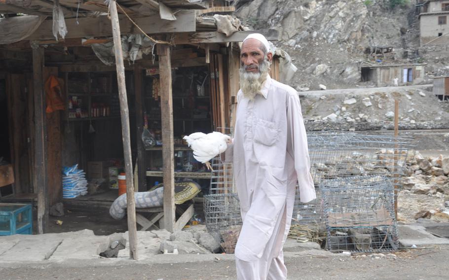A man carries a chicken in the Kandagal Bazaar on July 21. The village is just across the Pech River and down the road from Combat Outpost Michigan.