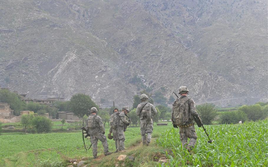 Mountains where insurgents roam tower over U.S. soldiers searching on July 21 for hidden weapons in the fields of the hostile Chinar Village at the mouth of the Korengal Valley.