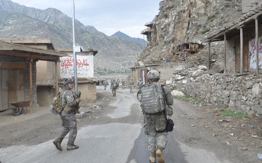 U.S. soldiers are dwarfed by the mountain walls along the Pech River as they walk back to base on July 21.