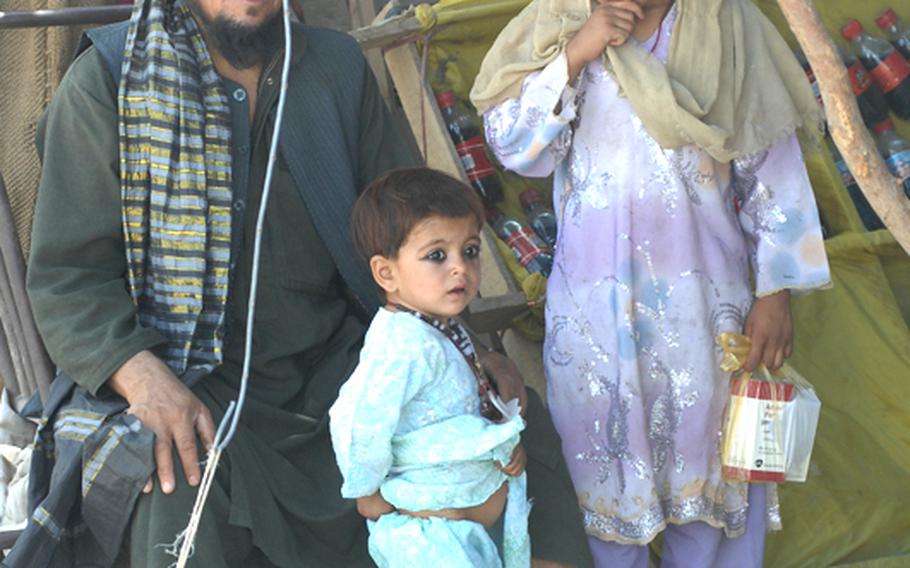 A family watches U.S. soldiers and Afghan National Police patrol in Kandahar province.