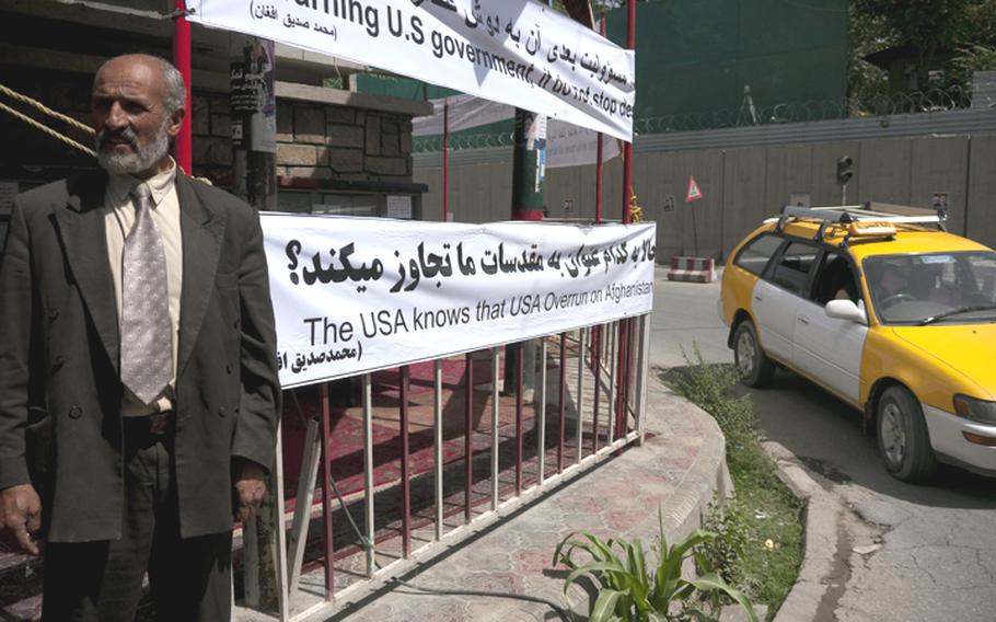 Across the street from a complex of U.S. and NATO bases in central Kabul, Mathematician Ghulam Farouk Hamkar stands next to a banner decrying plans by a small Florida church to burn copies of the Koran on the anniversary of Sept. 11. The plans have sparked widespread outrage among Afghans. The banner, somewhat imperfectly translated into English, reads in part: "I warning U.S. government, if do not stop desecrate to Islam profanity in their country, for further white house will be responsible."
