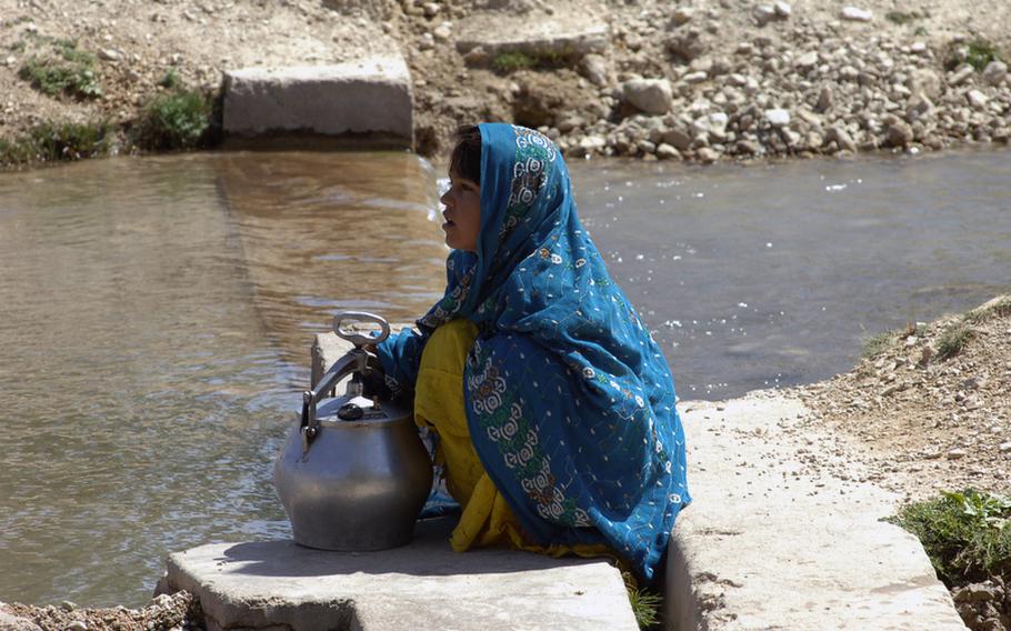 An Afghan girl takes water from one of the many cool streams flowing through Helal China, an isolated village in Zabul province's Shah Joy district.