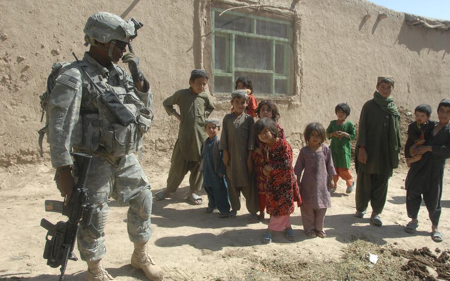 Cpl. Brandon Turner, 23, of Fort Pierce, Fla., converses in Pashto with children in Helal China, an isolated village in Zabul province's Shah Joy district.