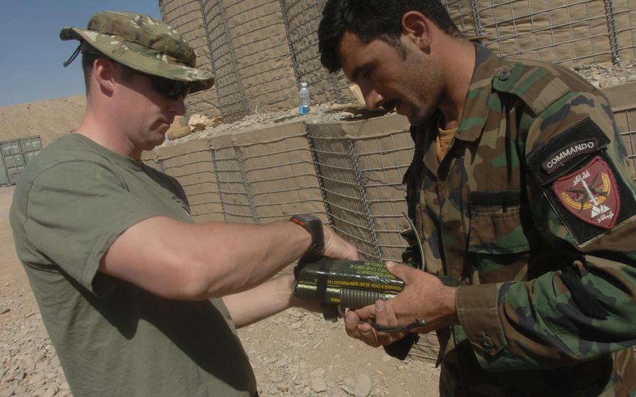 British Army Royal Engineers bomb disposal expert Sgt. Gerry Cooper, 34, of Scotland, shows an Afghan commando how to attach det cord to military grade explosives at Kandahar Air Field on Sunday, Sept. 26.