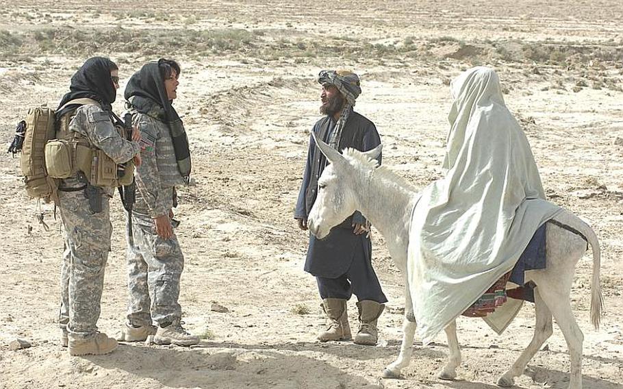 Female Engagement Team members Sgt.  Richelle Aus, 25, of Michigan City, Ind., and Laila Khoshnaw prepare to search a woman being led to a medical clinic on a donkey by her husband in Zabul province, Afghanistan.