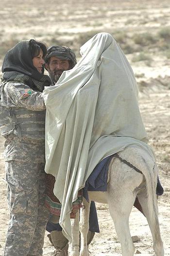 Female Engagement Team Laila Khoshnaw searches a woman being taken to a medical clinic on a donkey by her husband in Zabul province.