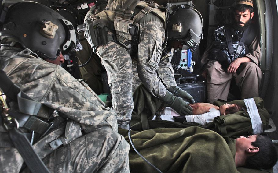 Crew chief Sgt. 1st Class Lloyd Swaby, 36, of Fort Lauderdale, Fla., left, and flight medic Staff Sgt. Rakheem Francis, 24, of Queens, N.Y., right, with the 101st Combat Aviation Brigade's Task Force Shadow, treat two Afghan children injured in a  Sept. 19 bomb blast in the Arghandab Valley in Kandahar province, Afghanistan, as a relative looks on. The two children survived.