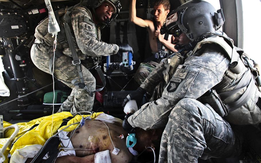 Flight medic Staff Sgt. Rakheem Francis, 24, of Queens, N.Y., (right) and crew chief Sgt. 1st Class Lloyd Swaby, 36, of Fort Lauderdale, Fla. (left), with the 101st Combat Aviation Brigade's Task Force Shadow, treat an Afghan soldier who was severely wounded Sept. 19 in a Taliban ambush near Kandahar as another wounded Afghan soldier looks on. The severely wounded soldier died a short while later.
