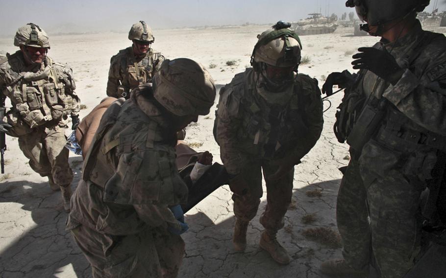 Canadian soldiers load a wounded Afghan soldier onto a U.S. helicopter ambulance, as Sgt. Patrick Schultz, 31, a flight medic with the 101st Combat Aviation Brigade&#39;s Task Force Shadow, looks on. The Afghan soldier was wounded in a Taliban attack south of Kandahar, Afghanistan. Sept. 21, 2010.