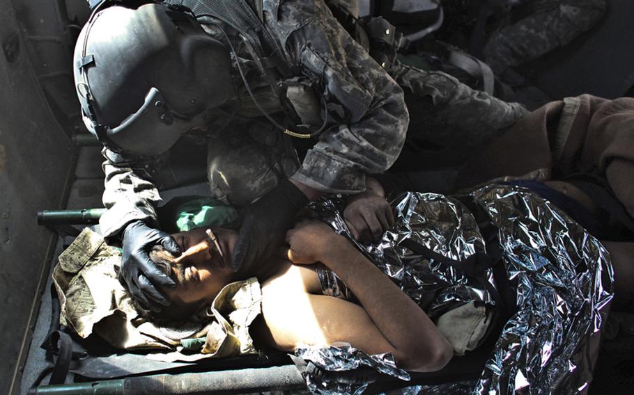 Sgt. Patrick Schultz, 31, a flight medic with the 101st Combat Aviation Brigade&#39;s Task Force Shadow, treats an Afghan soldier who was wounded in a Taliban attack south of Kandahar, Afghanistan. Sept. 21, 2010.