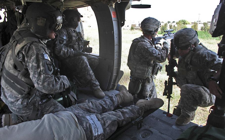 Sgt. Patrick Schultz, 31, of Louisville, Ky., (left), a flight medic with the 101st Combat Aviation Brigade&#39;s Task Force Shadow, looks on as two soldiers wounded in bomb blast  are loaded on to a helicopter ambulance near the city of Kandahar, Afghanistan. The soldier on the right is getting in the aircraft to help pull a stretcher bearing the second wounded soldier aboard. Sept. 21, 2010.