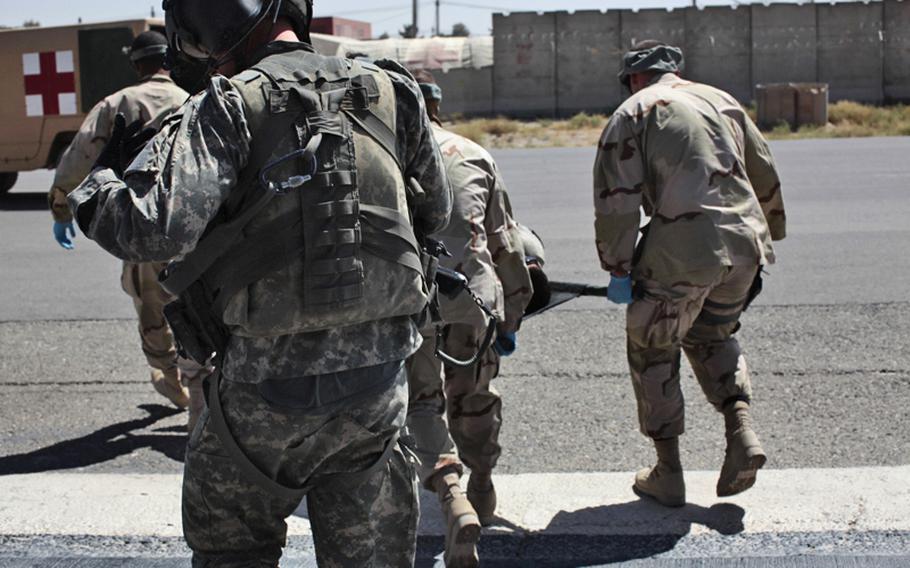 Sgt. Patrick Shultz, 31, of Louisville, Ky., a flight medic with the 101st Combat Aviation Brigade&#39;s Task Force Shadow, follows U.S. Navy medical personnel carrying a wounded soldier to a waiting ambulance at Kandahar Airfield, Afghanistan. Sept. 21, 2010.