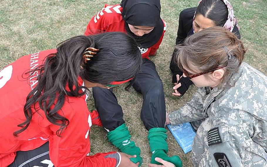 An American medic treats a member of the Afghan women's soccer team after she came off the pitch with a leg cramp during a match against the ISAF women's team at ISAF Headquarters in Kabul on Friday.