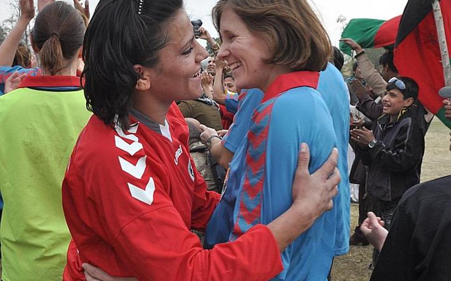 A member of the ISAF women's soccer team, in blue, embraces an Afghan women's national soccer team player after their game Friday at ISAF Headquarters in Kabul.