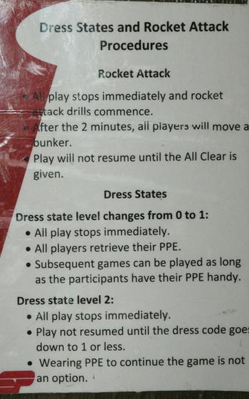 A sign outlines 'Dress States and Rocket Attack Procedures' next to the ball hockey rink at the boardwalk at Kandahar Air Field in southern Afghanistan.