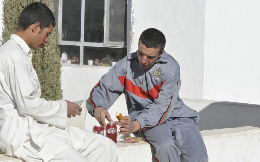 Police recruits at the Adraskan National Training Center in western Afghanistan dig into some holiday treats Tuesday during the first day of the Eid al-Adha holiday.