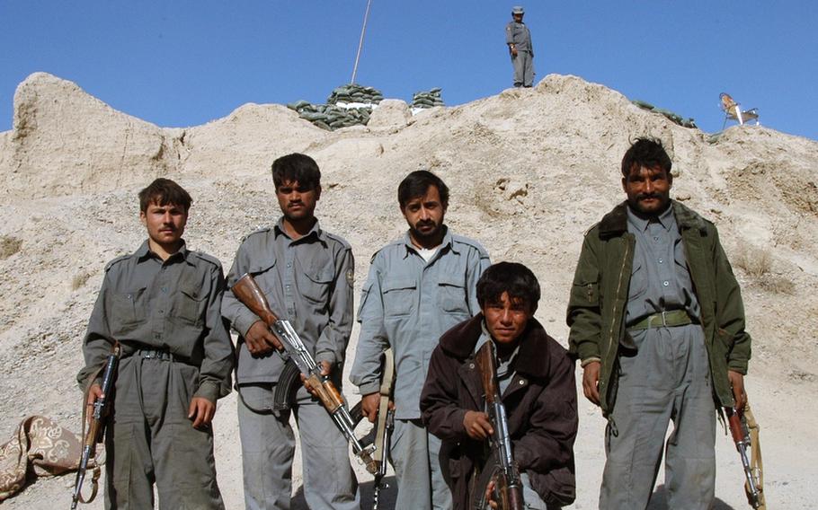 Members of the Afghan National Police pose in front of an earthen mound used as an observation point at Checkpoint Kupak in Garmsir District, Afghanistan. Members of the 2nd Battalion 1st Marines police advisory team live alongside the ANP officers at the checkpoint as part of a multi-faceted approach to training up the local security forces so they are ready to take on the Taliban when coalition forces withdraw from their country.