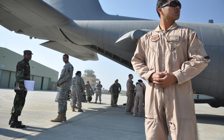 Staff Sgt. Lloyd Guerrero stands guard as a Pakistani customs inspector looks on while cargo is off-loaded from a U.S. Air Force C-130 at a small airstrip in Ghazi, Pakistan.