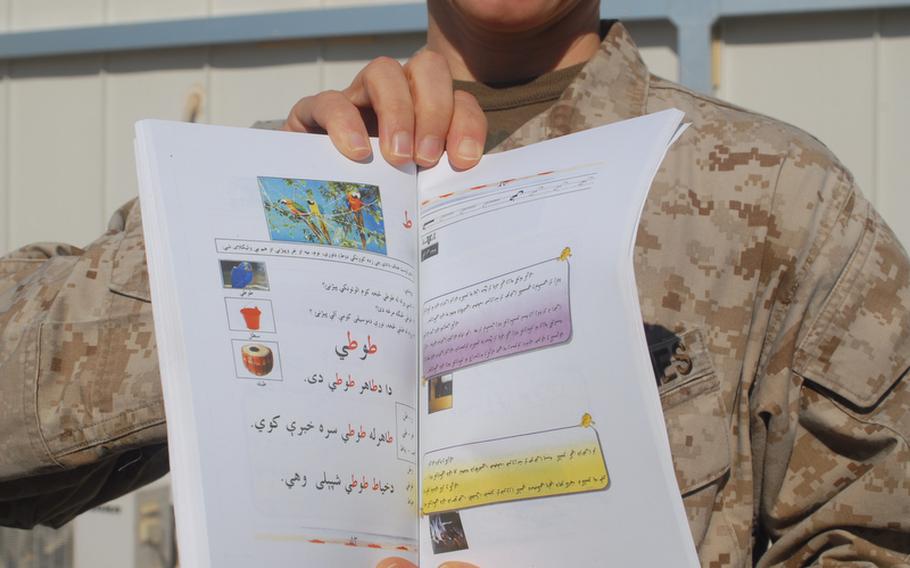Maj. Nina D'Amato holds up one of 70,000 booklets to be distributed in rural Helmand province for women to learn to read in their homes as
they listen to teachers on a daily radio program.
