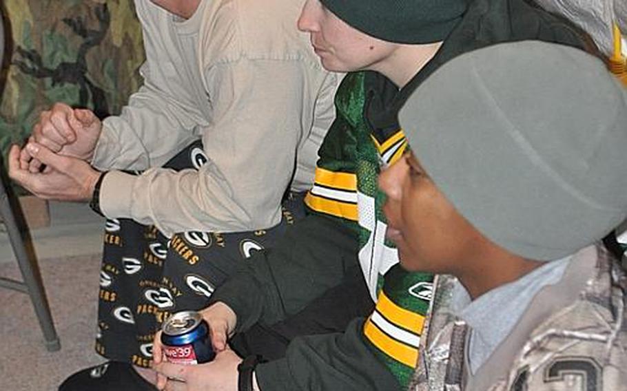 From left to right, 1st Sgt. Brandon Perry, 37; Sgt. Kali Tackitt, 23; and Spc. Natalie Smith, 24, watch the Packers and the Steelers go at it in Super Bowl XLV at icy Forward Operating Base Sharana in Paktika province in eastern Afghanistan.