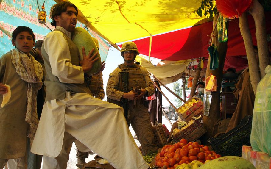 Marine Capt. Mike Regner buys a watermelon at Nawa's main bazaar May 6, 2011. The Marines are paying to refurbish a large part of the bazaar at a cost of $200,000. Last year, they spent $200,000 to build a new row of shop stalls across the way from this stall using CERP, or commander's emergency response program funds, which are generally used for quick-impact projects.