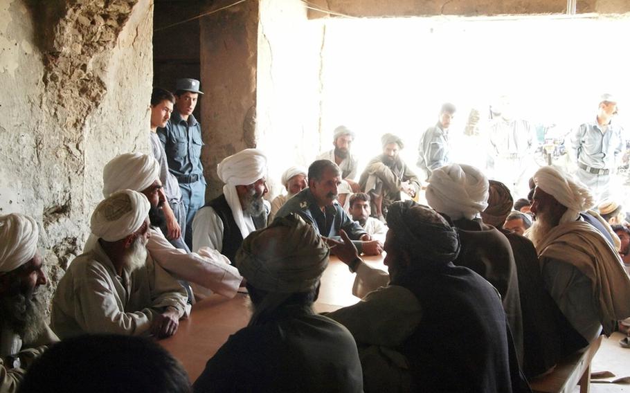 Nawa District Chief of Police Maj. Sayfullah, who goes by one name, meets with workers and a representative of a contractor to resolve a pay dispute May 11, 2011.
